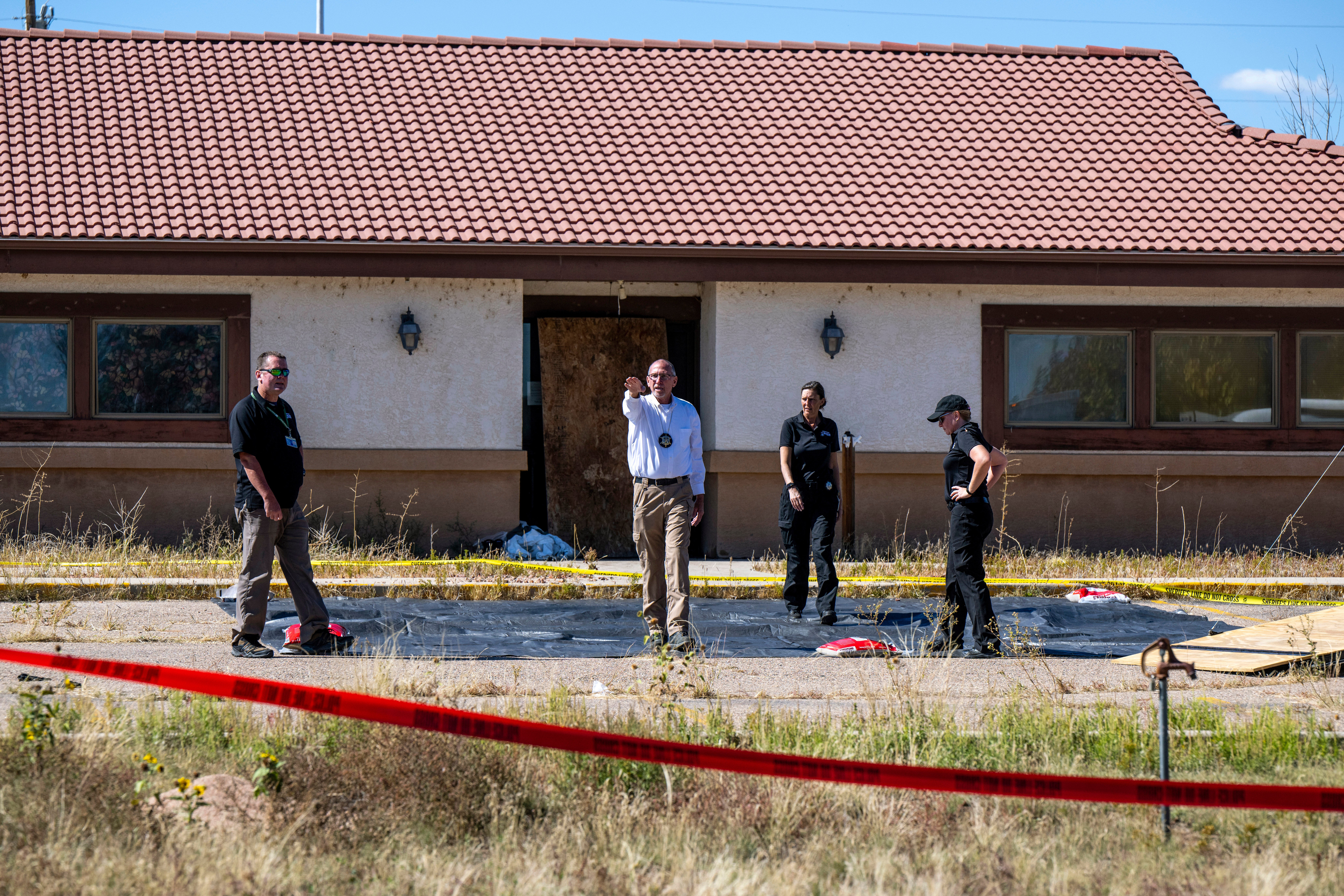 Fremont County coroner Randy Keller, center, and other authorities survey the area where they plan to put up tents at the Return to Nature Funeral Home where more than 100 bodies have been improperly stored